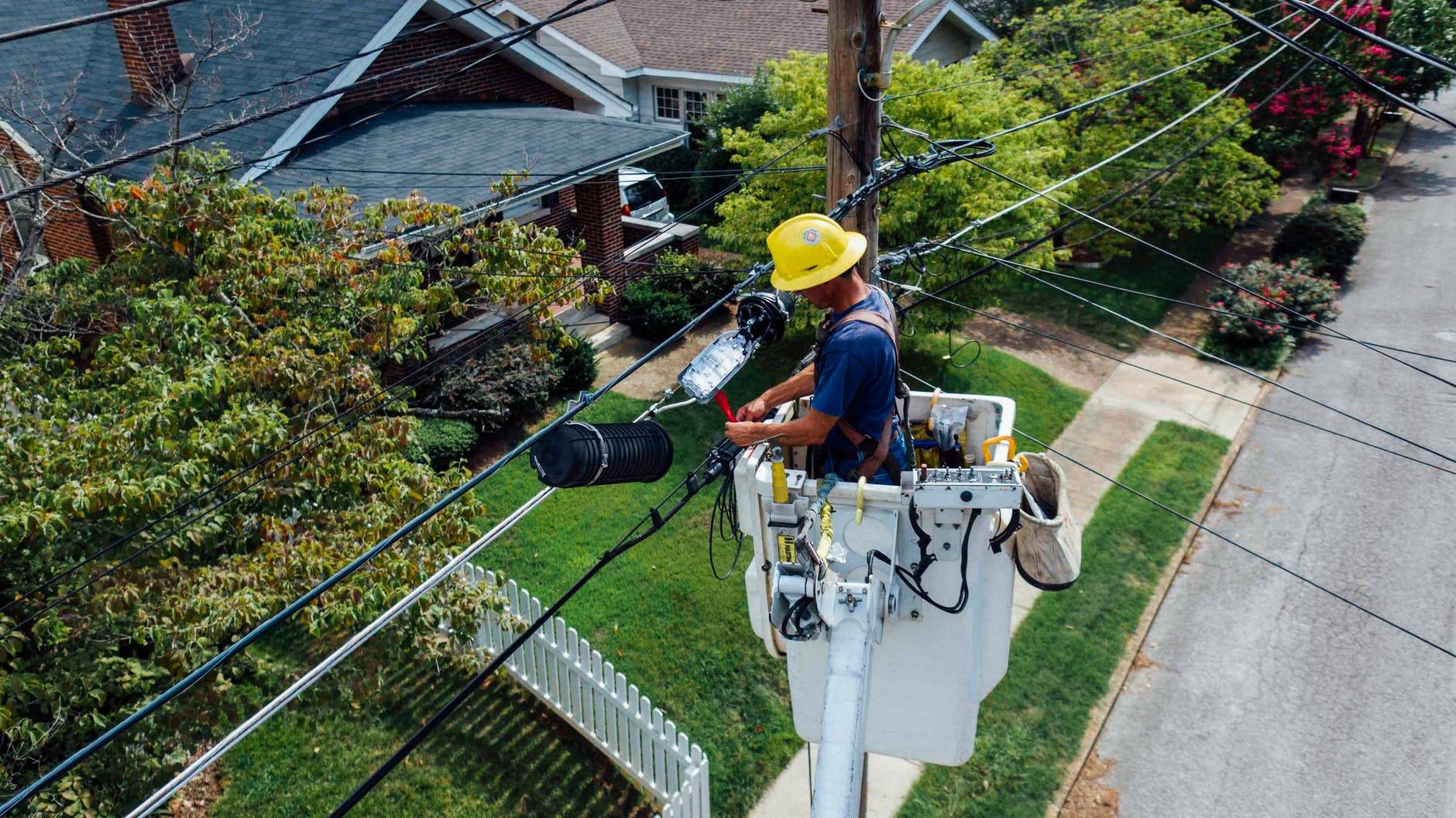 photography of man repairing electrical wires